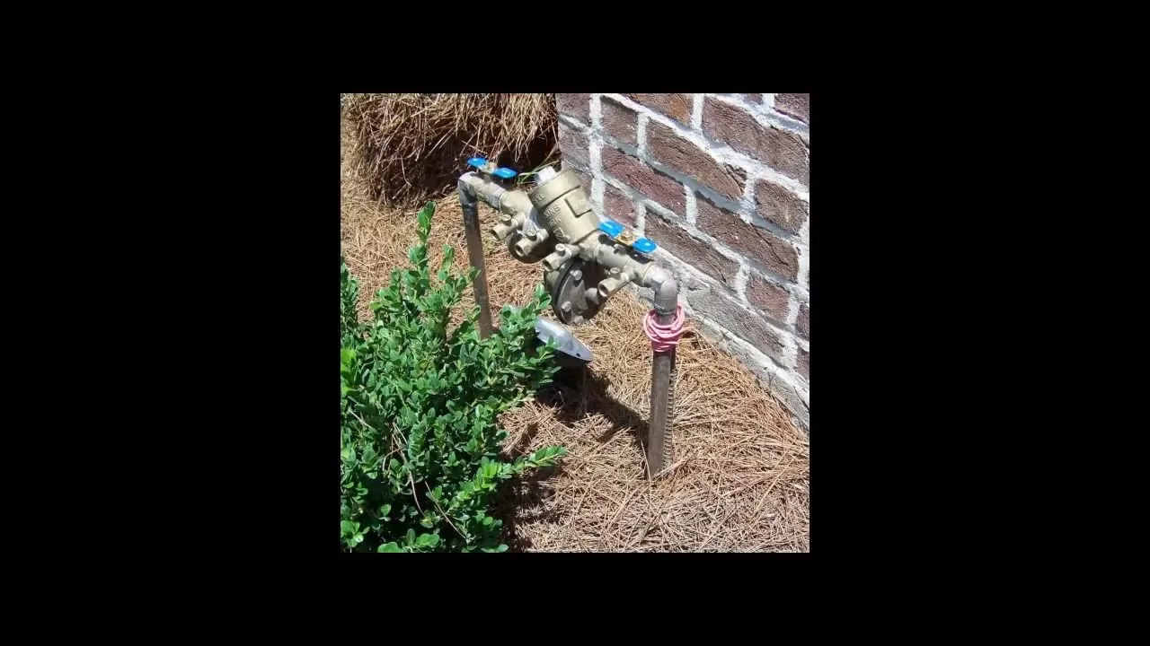 Irrigation backflow valves beside brick wall, part of a owasa backflow requirements visit in Chapel Hill, NC