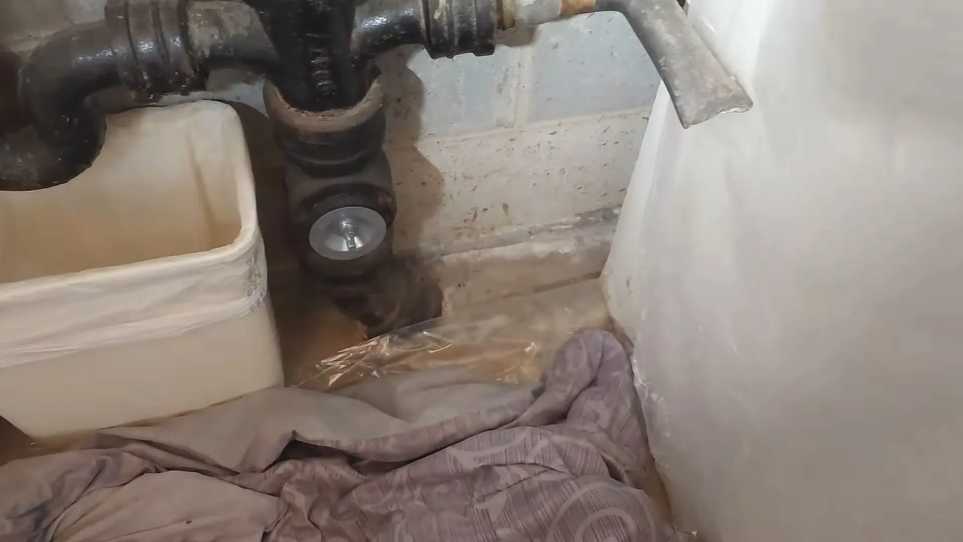 A technician working on damaged cast iron drain at bathroom floor during a shutting off your water main call near Chapel Hill