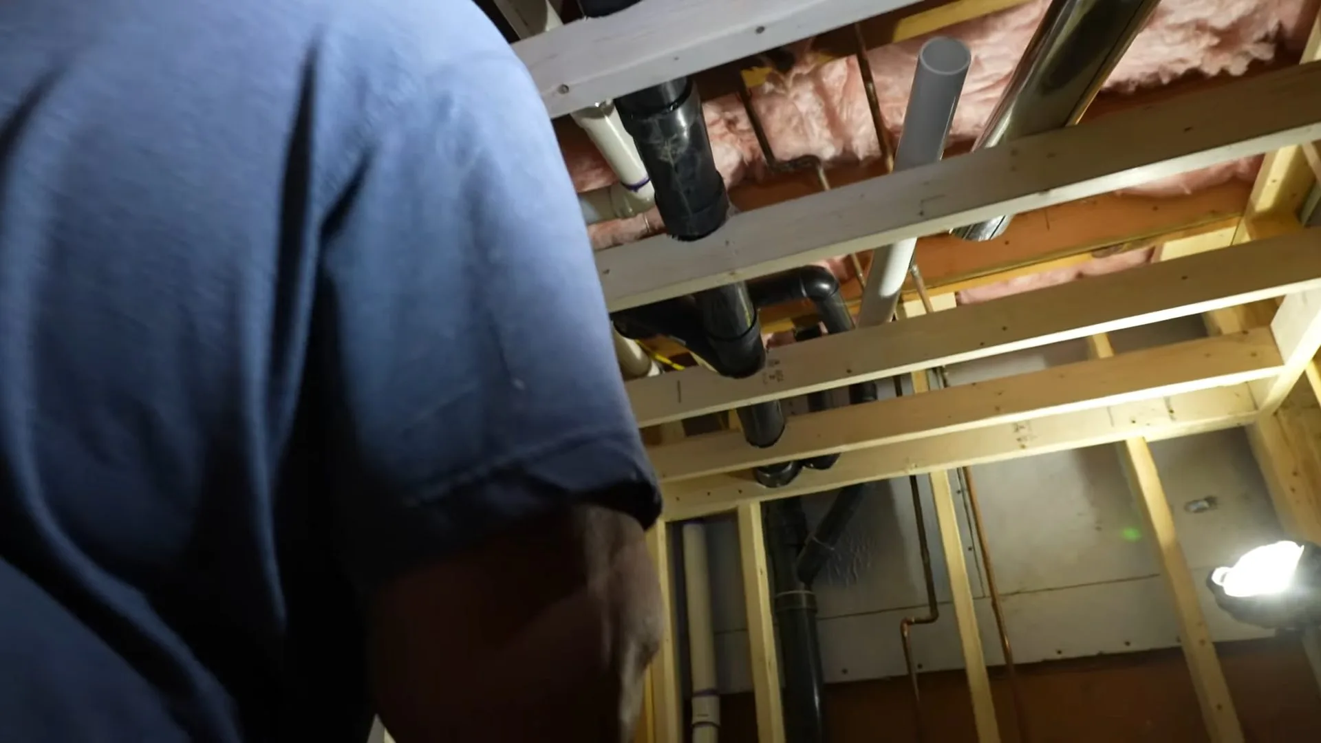 Plumber installing basement vent pipe photographed on site during septic vs. sewer systems work