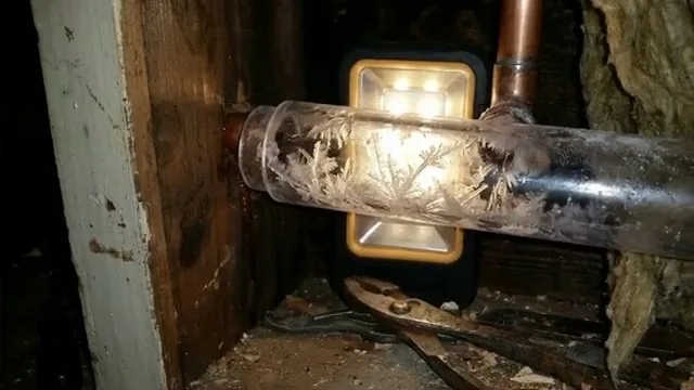 Warming frozen pipe with hair dryer, documented during sump pump battery backup service in the Chapel Hill area