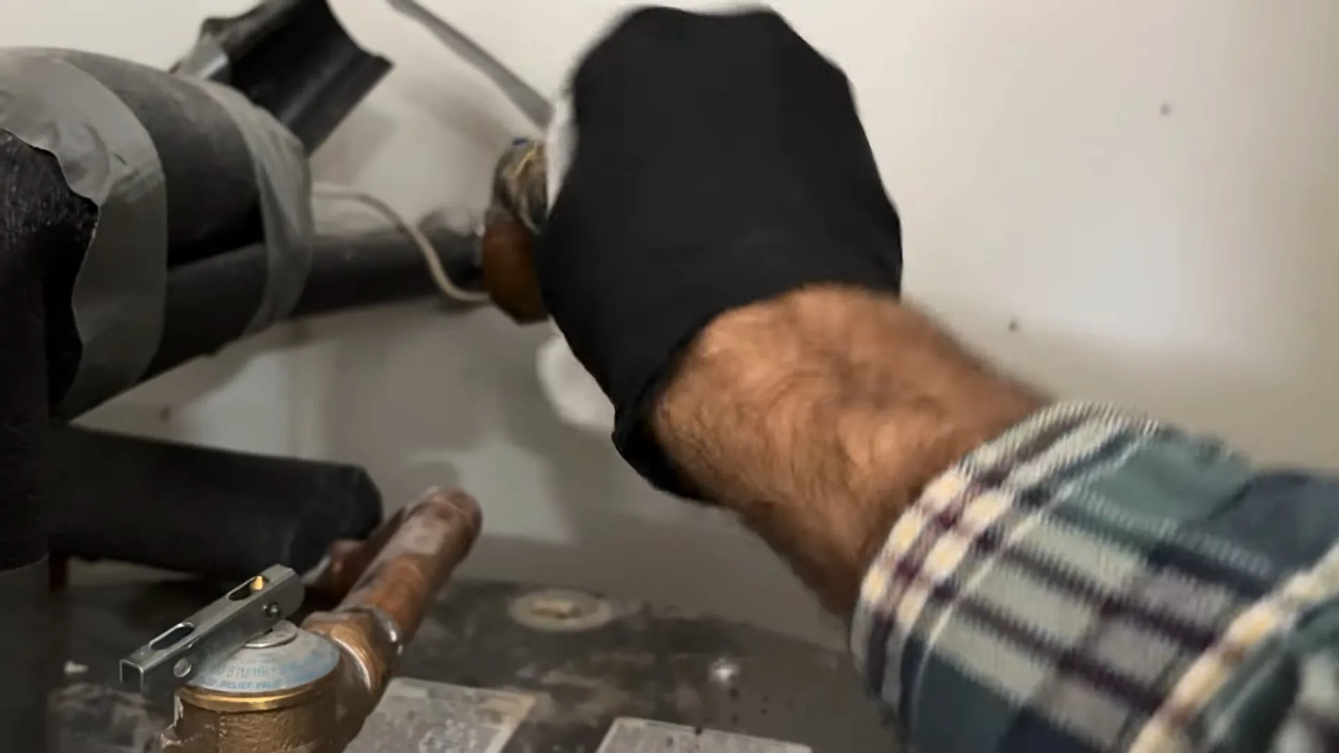 Close view of technician fixing water heater inlet hose handled during a water heater lifespan guide appointment